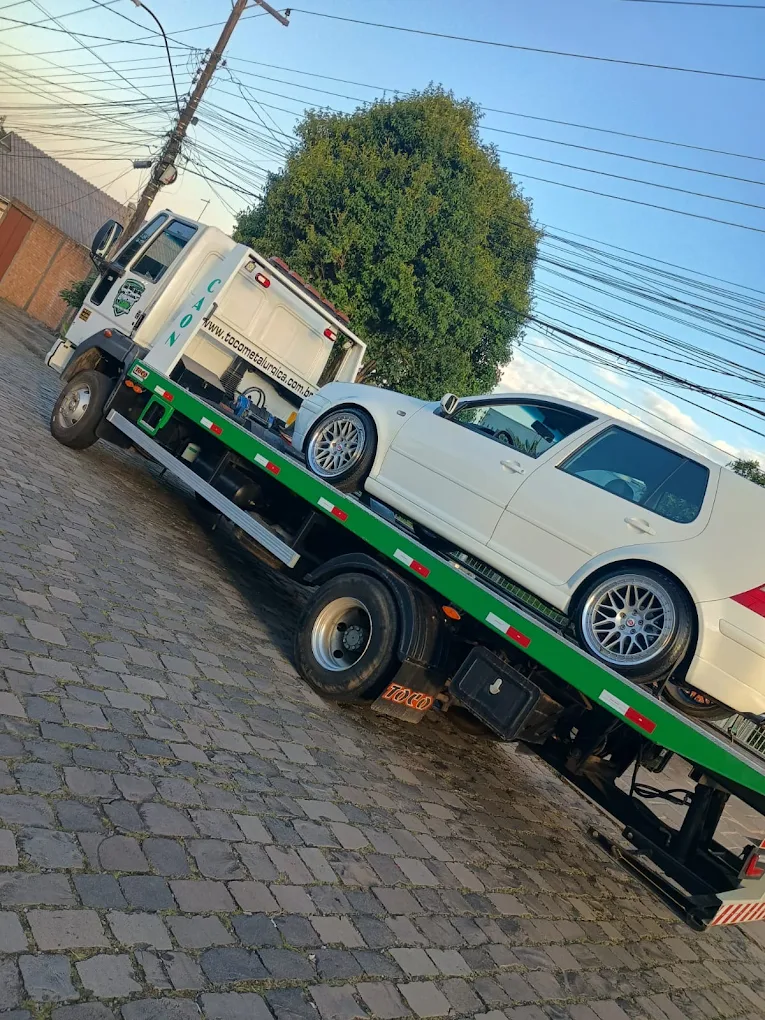 Carro branco sendo transportado no guincho